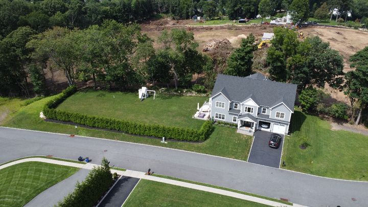 Aerial view of a house and lawn with a planted privacy row following the street frontage.