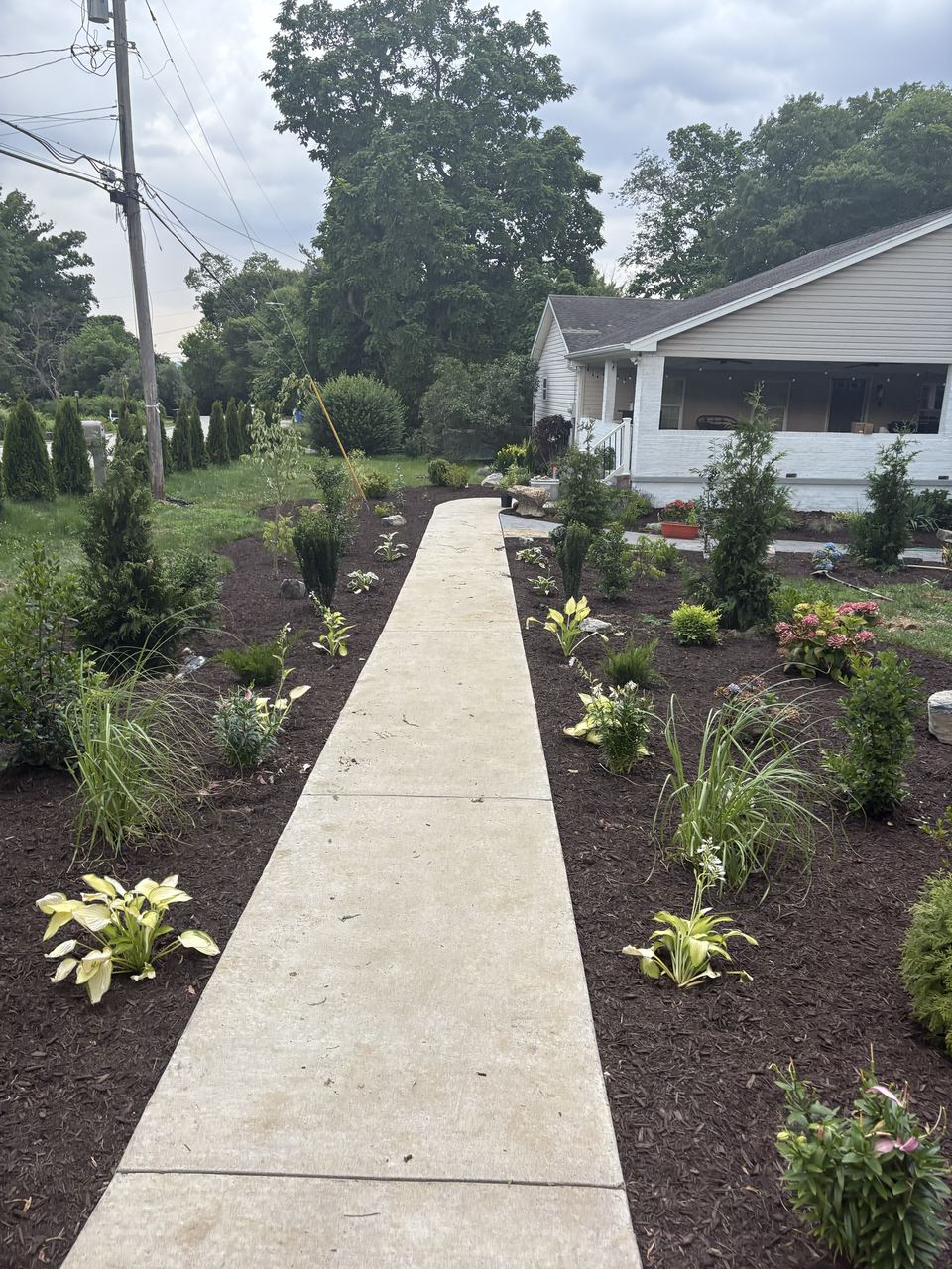 Planting beds on both sides of a walkway leading toward a house.